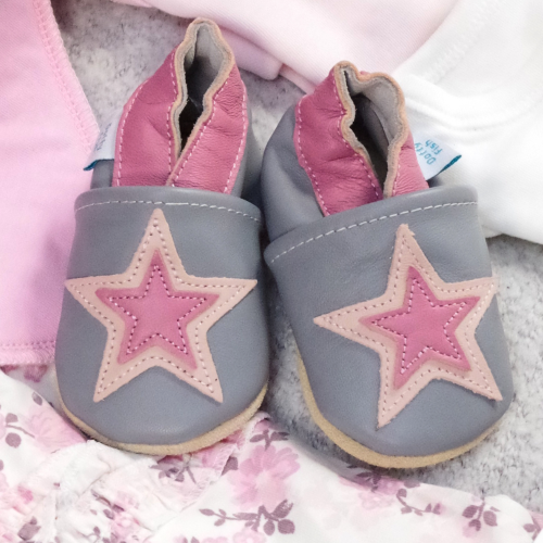 Grey and pink leather shoes in drawer with baby clothing.