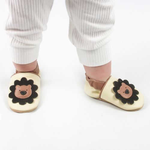 Baby wearing cream Dotty Fish shoes with lion design and white baby grow.