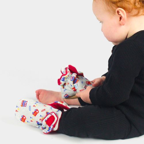 Sitting toddler, wearing pale grey baby booties in vehicles design.