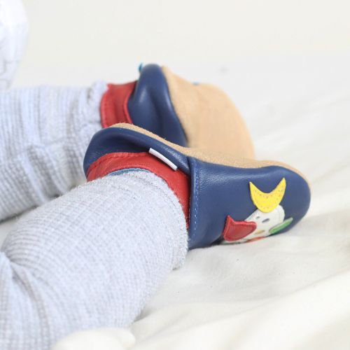 Baby wearing blue Dotty Fish soft sole infant shoes with multicoloured fish design.