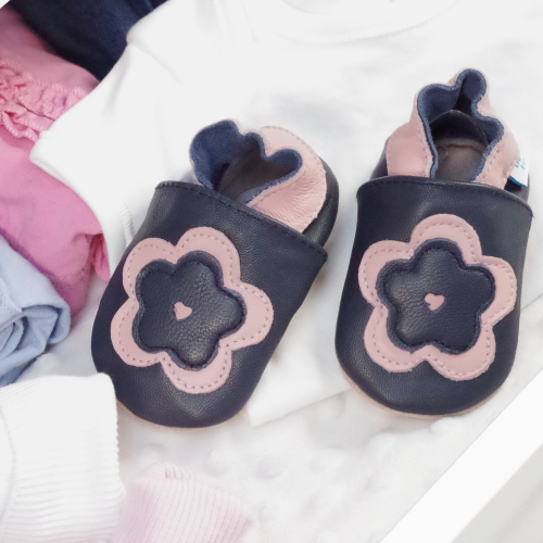 Leather navy and pink flower shoes in drawer with baby clothing.