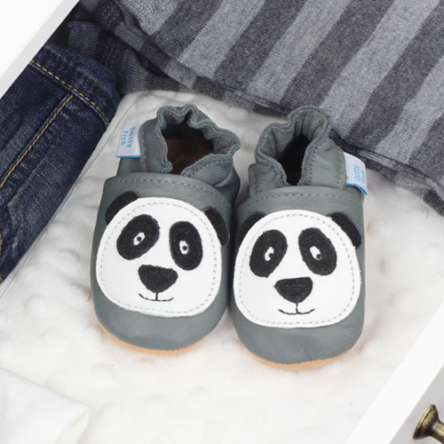 Grey leather shoes with panda design, in drawer with baby clothing.
