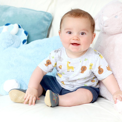 Baby boy sitting, wearing grey Dotty Fish barefoot shoes with embroidered rainbow star design.