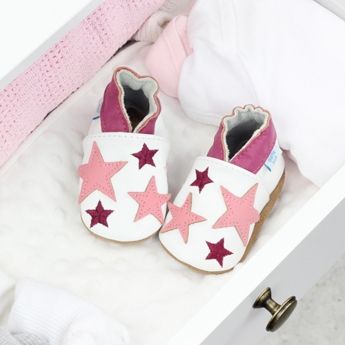White leather shoes with pink stars, in drawer with baby clothing.