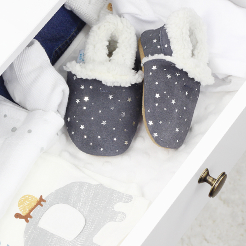 Dark grey suede slippers with silver stars sitting in drawer.