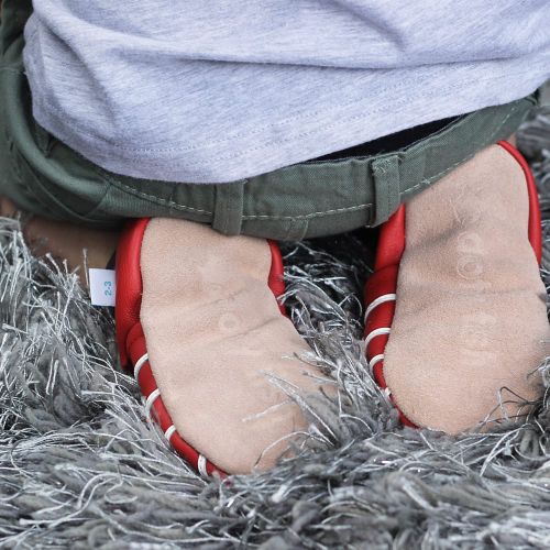 Toddler kneeling on floor showing suede soles of Dotty Fish shoes.