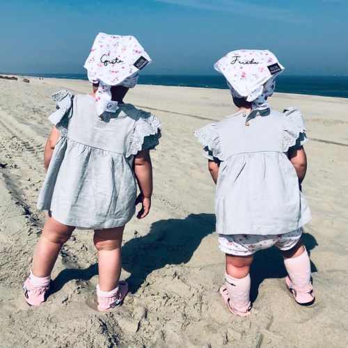 Two toddlers on beach, wearing Dotty Fish pink flower sandals.