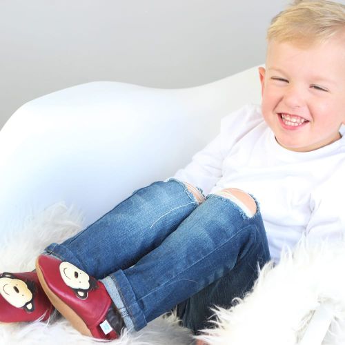 Small boy sitting wearing red Dotty Fish monkey shoes.