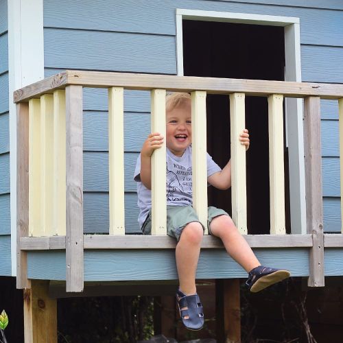 Small boy wearing navy leather Dotty Fish first walker barefoot sandals, sitting outside.