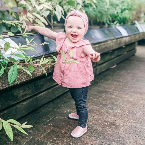 Little girl wearing Dotty Fish pink leather pre-walker rubber sole slip-on shoes.