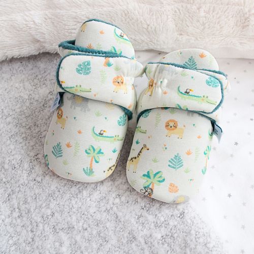 Cream safari baby booties, sitting with blankets.