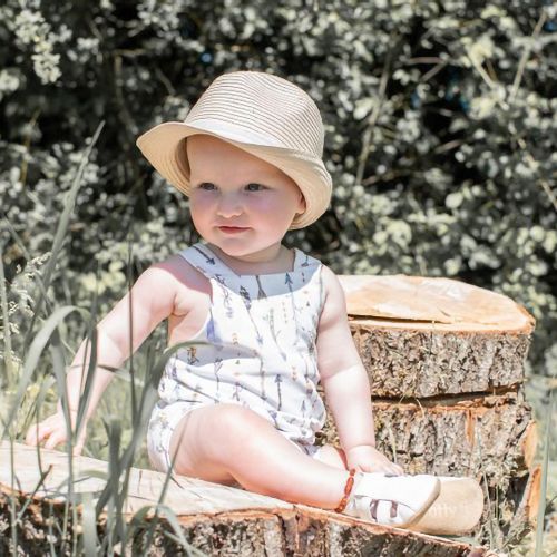 Small girl sitting outside in sunshine, wearing white leather Dotty Fish first walker barefoot sandals.