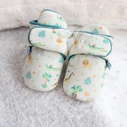 Cream safari baby booties, sitting with blankets.